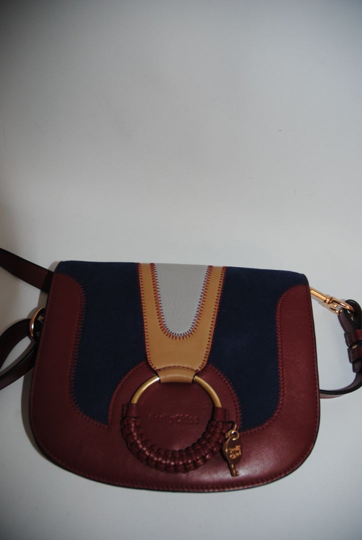 Body: Navy blue suede Trim & Strap: Burgundy and camel-toned smooth leather See by Chloe Hana Small Saddle Bag, Width: 7.5 in (19 cm) Height: 6.5 in (16.5 cm) Depth: 2.75 in (7 cm) Strap Drop: Adjustable up to approx. 22 in (crossbody length)