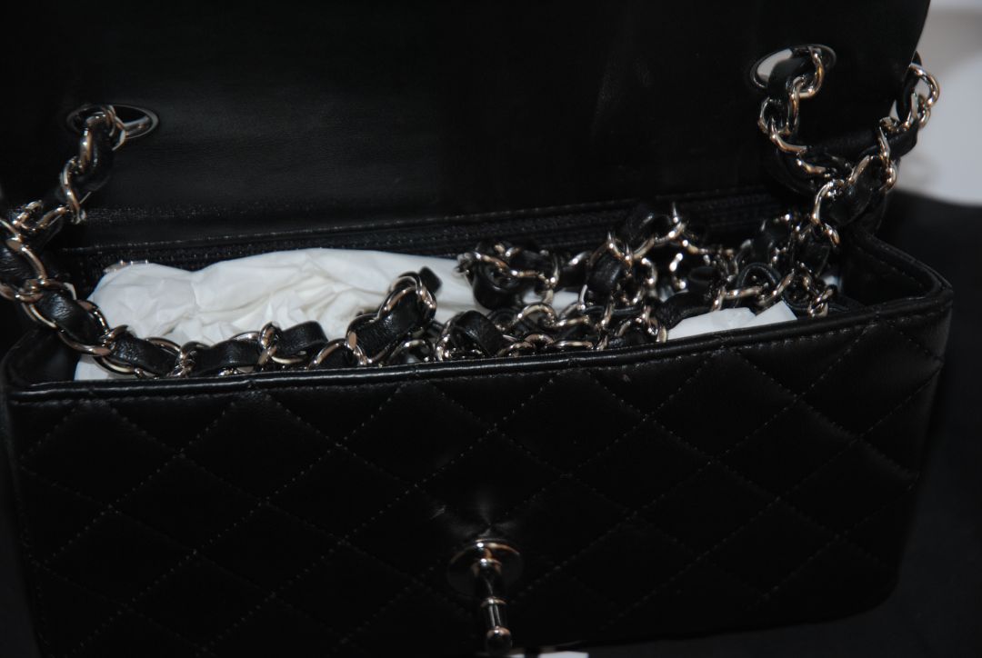 black lambskin Chanel classic flap bag, approx 25.5 cm (W) × 16 cm (H) × 7 cm (D) (≈ 10″ × 6.3″ × 2.75″) per size guide.