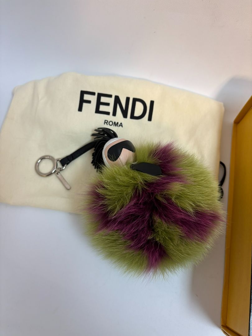purple and green FENDI fur “monster” bag charm, pom-pom diameter: 10 cm (4 in) Total hanging drop (ring + strap + fur): ~20 cm (8 in)
