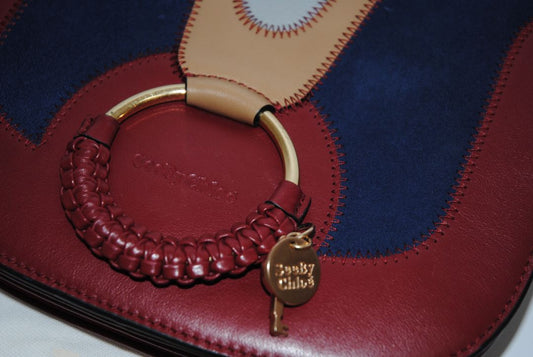 Body: Navy blue suede Trim & Strap: Burgundy and camel-toned smooth leather See by Chloe Hana Small Saddle Bag, Width: 7.5 in (19 cm) Height: 6.5 in (16.5 cm) Depth: 2.75 in (7 cm) Strap Drop: Adjustable up to approx. 22 in (crossbody length)