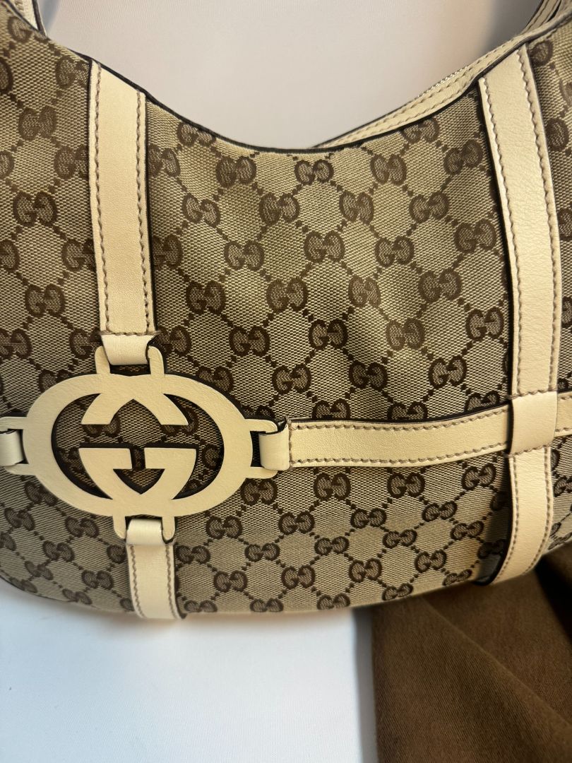 Gucci Monogram GG Royal Hobo bag in off-white, featuring the iconic GG monogram canvas, a soft hobo silhouette, and brown leather trim. The bag is accented with gold-tone hardware and a spacious interior, making it a stylish and practical choice for everyday wear.