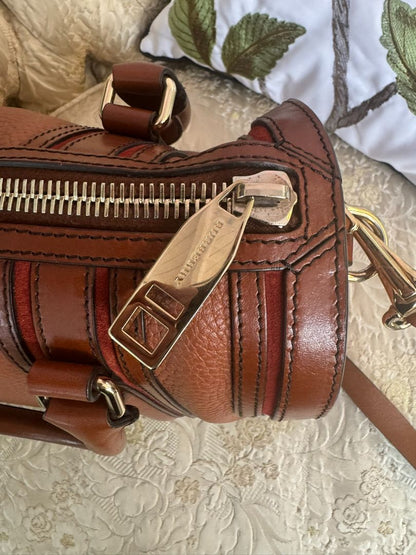 Cognac brown with multi-stripe accents in oxblood, black, and tan (subtle nod to Burberry’s house check palette) Burberry Model: Likely from the Banner or Orchard satchel line (structured silhouette with rolled handles and stripe accents), Length: 13 in (
