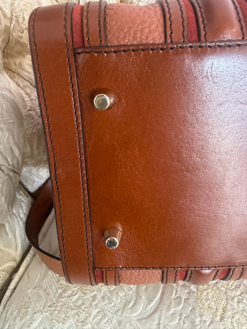 Cognac brown with multi-stripe accents in oxblood, black, and tan (subtle nod to Burberry’s house check palette) Burberry Model: Likely from the Banner or Orchard satchel line (structured silhouette with rolled handles and stripe accents), Length: 13 in (