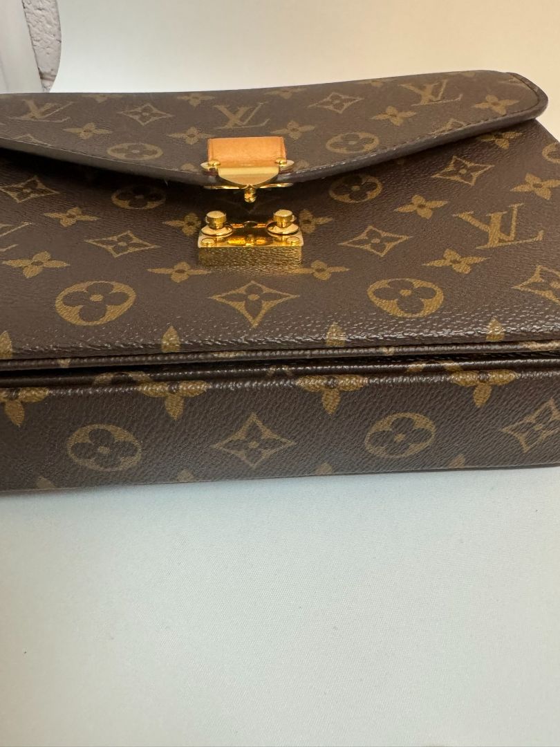 Louis Vuitton Pochette Métis in Monogram canvas, featuring the iconic LV logo print, a structured flap design, gold-tone hardware, and a detachable shoulder strap for versatile wear. This elegant crossbody bag is perfect for both day and night occasions.