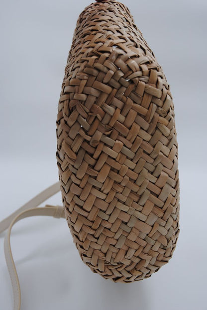 Mini woven seagrass crossbody basket bag with a natural finish and adjustable strap.
