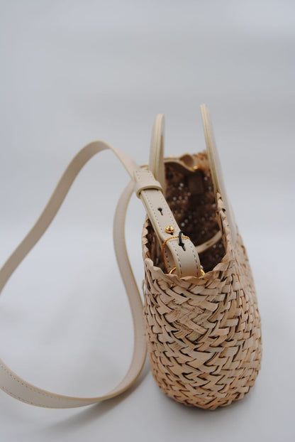 Mini woven seagrass crossbody basket bag with a natural finish and adjustable strap.