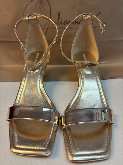 Vince Camuto gold strappy sandals with metallic finish, slim toe and ankle straps, and stiletto heel. New with tags, size 8M, displayed against a plain background.